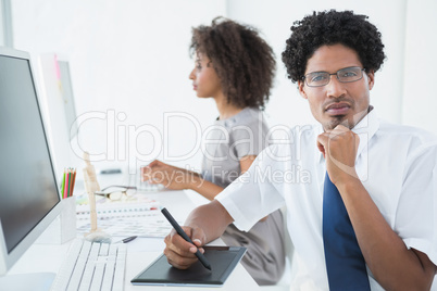 Young designer looking at camera at his desk