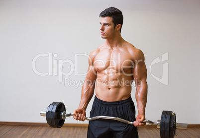 Shirtless muscular man lifting barbell in gym