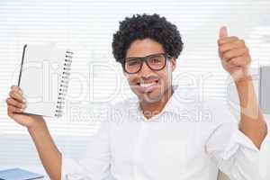 Happy businessman showing notepad and thumbs up