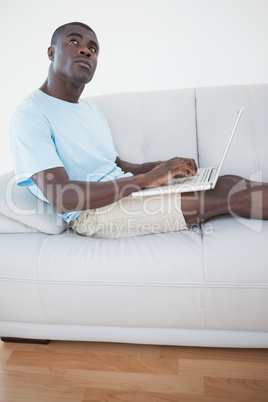 Casual man sitting on sofa using laptop