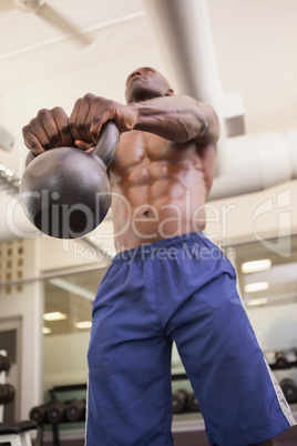 Muscular man lifting kettle bell in gym