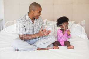 Father and baby girl sitting on bed together