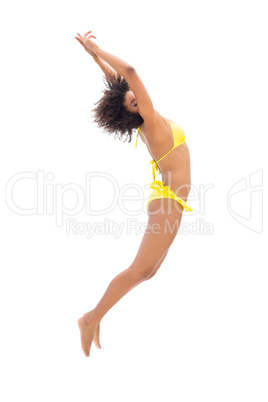 Fit girl in yellow bikini jumping and stretching