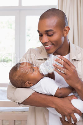 Happy father feeding his baby boy a bottle