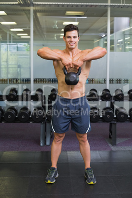 Muscular man lifting kettle bell in gym