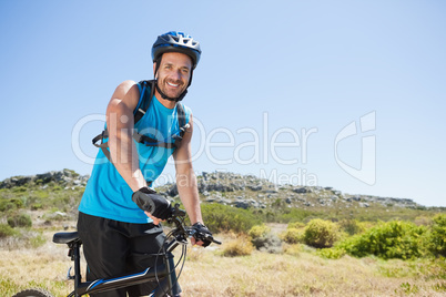 Fit cyclist riding in the countryside smiling at camera