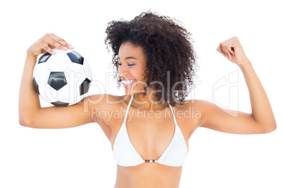 Smiling fit girl in white bikini holding football