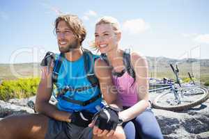 Fit cyclist couple taking a break on rocky peak