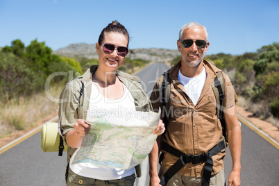 Hiking couple looking at map on the road