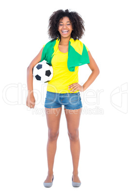 Pretty football fan holding brazilian flag smiling at camera