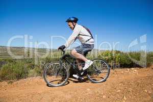 Fit cyclist riding on country terrain
