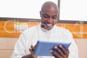 Happy man in bathrobe using tablet pc