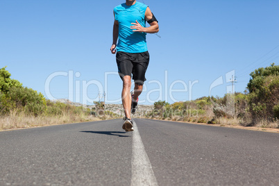 Athletic man jogging on open road