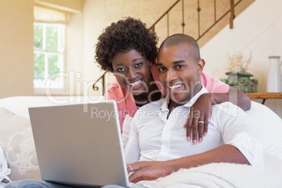 Cute couple relaxing on couch with laptop