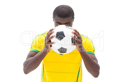 Nervous brazilian football fan hiding behind ball