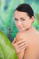 Beautiful nude brunette posing with green leaves