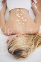 Beautiful blonde lying on massage table with petals on back