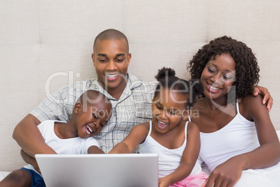 Happy family using laptop together on bed