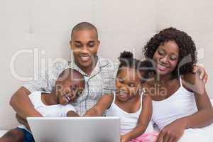 Happy family using laptop together on bed