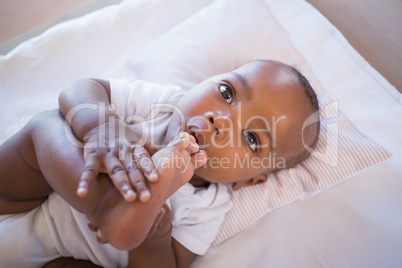 Adorable baby boy lying in his crib holding foot