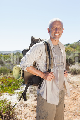 Handsome hiker smiling at camera in the countryside