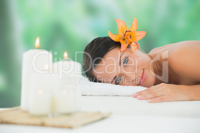 Beautiful brunette relaxing on massage table smiling at camera