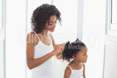 Pretty mother brushing her daughters hair