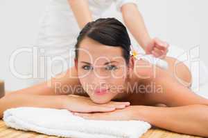 Peaceful brunette enjoying a herbal compress massage smiling at