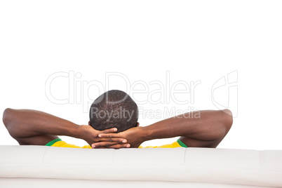 Man sitting on sofa with hands behind head