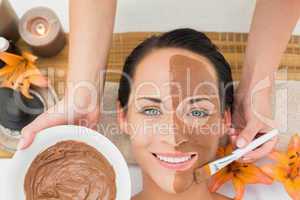 Peaceful brunette getting a mud facial applied