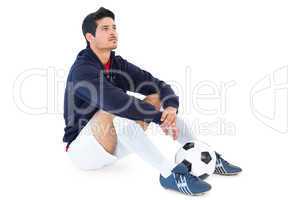 Football player sitting with ball