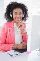 Casual graphic designer working at her desk smiling at camera