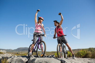 Fit cyclist couple cheering at the summit