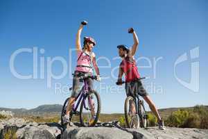 Fit cyclist couple cheering at the summit