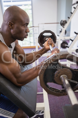 Determined muscular man lifting barbell in gym