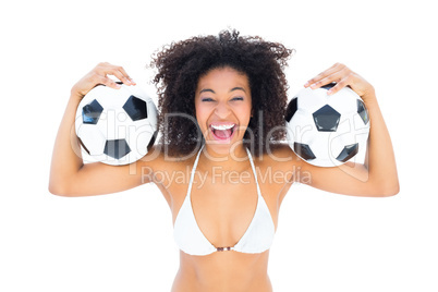 Excited fit girl in white bikini holding football