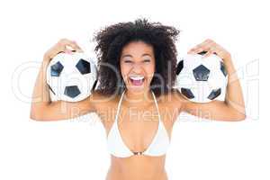 Excited fit girl in white bikini holding football