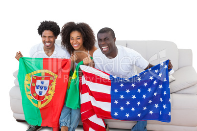 Cheering football fans holding flags on the sofa
