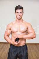 Body builder holding bottle with supplements in gym