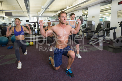 Fitness class lifting barbells together