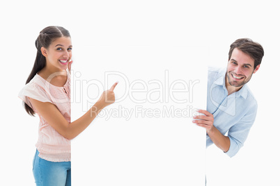 Attractive young couple smiling and holding poster