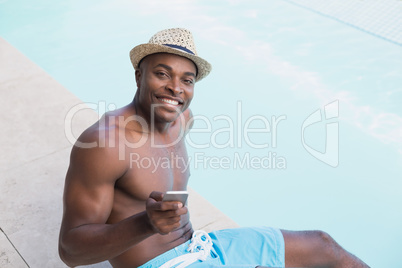 Handsome shirtless man texting on phone poolside