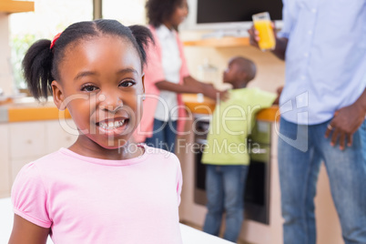 Cute little girl smiling at camera with family in background