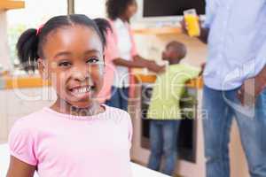 Cute little girl smiling at camera with family in background