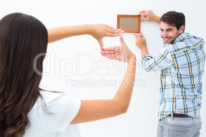 Happy young couple putting up picture frame