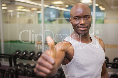 Muscular man giving thumbs up in gym