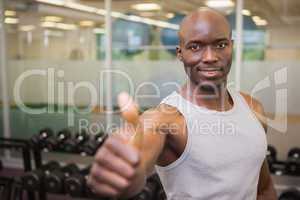 Muscular man giving thumbs up in gym