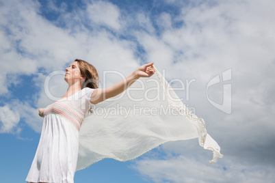 Woman holding out scarf against blue sky and clouds