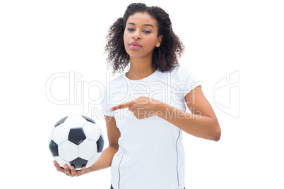 Pretty football fan in white holding ball and pointing to it