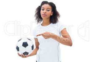 Pretty football fan in white holding ball and pointing to it